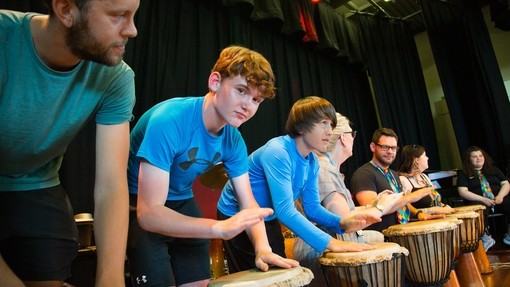 Students playing bongos in a row on stage 
