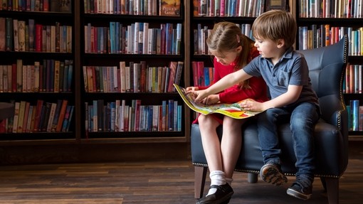 Two children reading a book in a library
